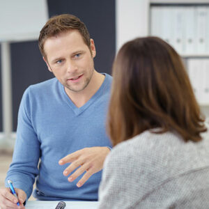 Homme de face, conseillant une femme assise face à lui - vue de dos)